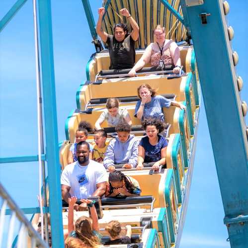 A group of children and adults enjoy a ride on a Ferris wheel, smiling and laughing under a clear blue sky.