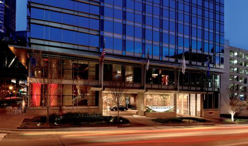 Exterior view of the Ritz-Carlton hotel at dusk, featuring modern architecture and illuminated entrance.