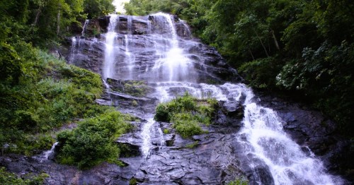 Views of Amicalola Falls in Georgia, a cascading waterfall surrounded by lush green foliage and rocky terrain.