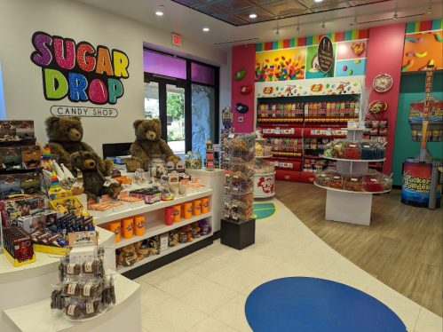 Brightly colored candy shop interior with shelves of sweets, stuffed bears, and a vibrant decor.
