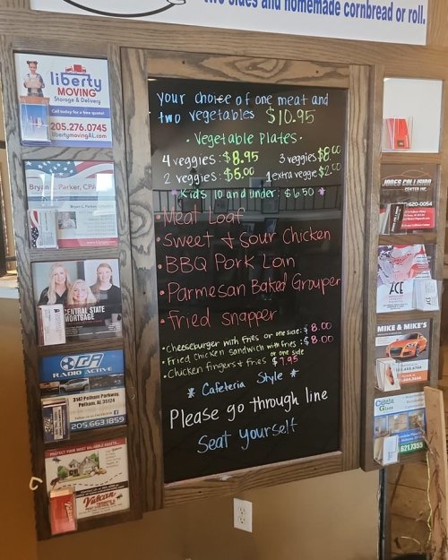 Menu board displaying daily specials and prices for meat and vegetable plates, with various meal options listed.