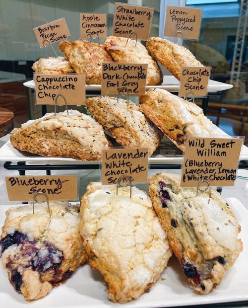 A display of assorted scones with labels, including flavors like blueberry, lavender white chocolate, and chocolate chip.