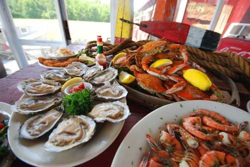 A platter of fresh seafood featuring oysters, shrimp, and crabs, garnished with lemon and herbs.