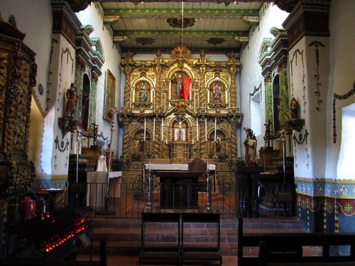 Interior of a richly decorated chapel featuring an ornate altar with gold accents and religious statues.