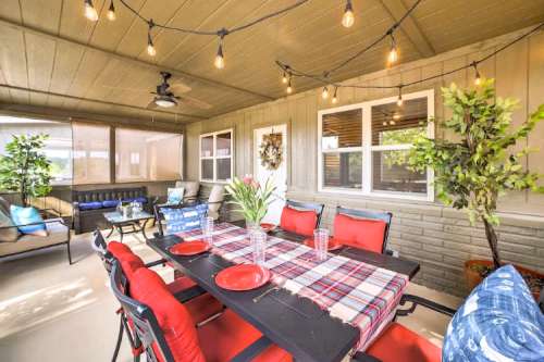 Cozy patio with a dining table, red chairs, potted plants, and string lights, creating a welcoming outdoor space.