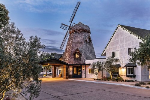 A charming building with a windmill, surrounded by trees, under a twilight sky.
