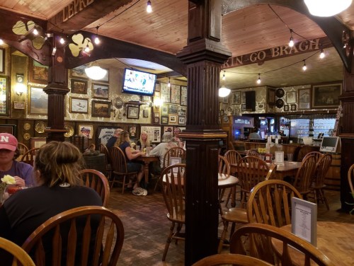 A cozy restaurant interior with wooden tables, framed photos on the walls, and patrons enjoying their meals.