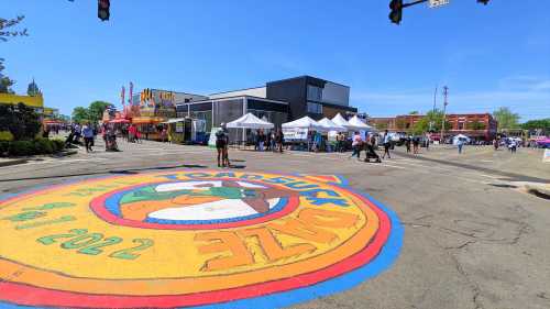 Colorful street mural for the Toad Suck Daze festival, with vendors and people enjoying a sunny day.