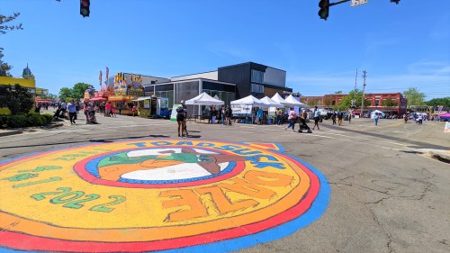 Colorful street mural for Toad Suck Daze festival, with vendors and people enjoying a sunny day in the background.