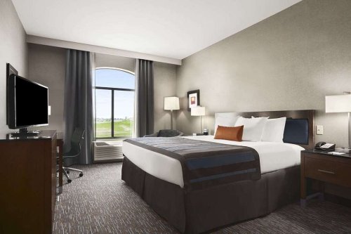 A modern hotel room featuring a king bed, desk, TV, and large window with a view.