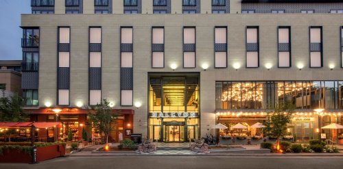 Exterior view of the Halcyon hotel, featuring modern architecture, outdoor seating, and warm lighting at dusk.