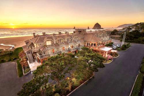 A coastal hotel at sunset, with ocean views and rocky formations in the background, surrounded by lush greenery.