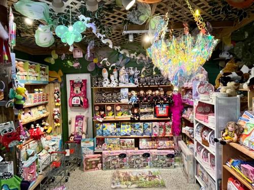 A colorful toy store display filled with stuffed animals, dolls, games, and decorative lights.
