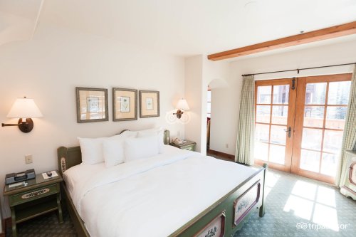 Cozy hotel room with a large bed, framed artwork, and a balcony door leading to an outdoor view.