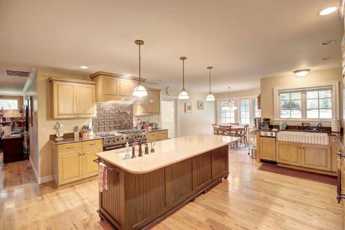 Spacious kitchen with wooden cabinets, an island, and dining area, featuring warm lighting and a cozy atmosphere.