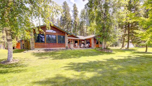 A cozy wooden cabin surrounded by trees and a lush green lawn, featuring a patio with seating.