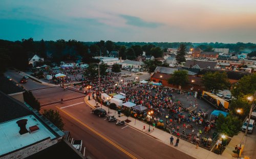 Aerial view of a bustling town square filled with people enjoying an outdoor event at sunset.