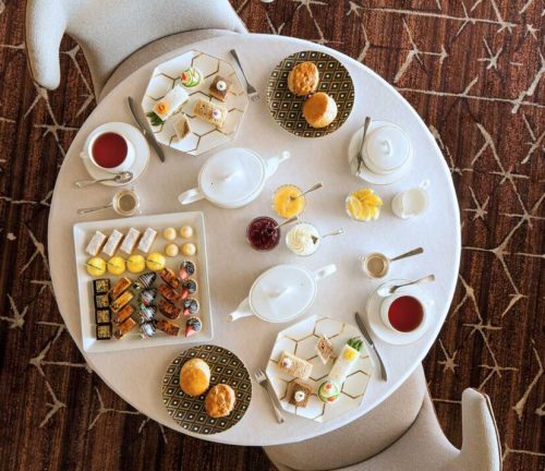 A round table set with an assortment of pastries, tea, and desserts, surrounded by elegant tableware.
