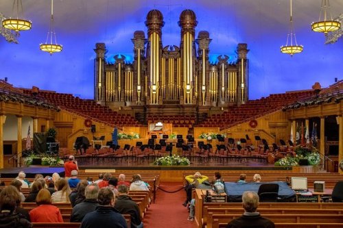 A concert hall with a large organ, empty seats, and a stage set for an orchestra performance.
