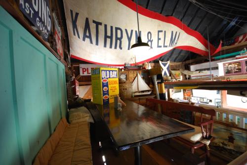 A cozy interior with a long table, colorful signs, and a large banner reading "KATHRYN & ELM" hanging above.