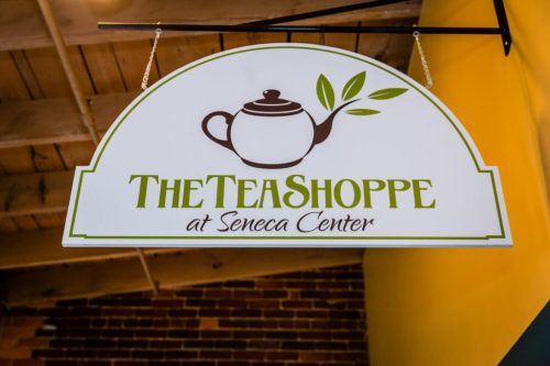 Sign for "The Tea Shoppe at Seneca Center" featuring a teapot and green leaf design.