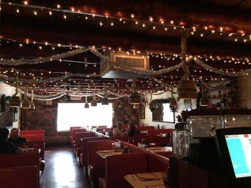 Cozy restaurant interior decorated with string lights and festive garlands, featuring red booths and a warm atmosphere.