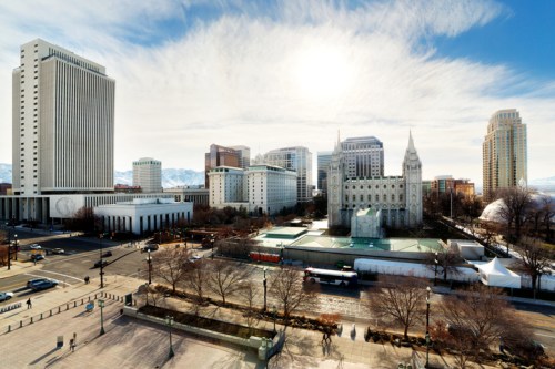 A panoramic view of a city skyline featuring modern buildings and a historic temple under a bright sky.