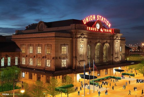 Historic Union Station at dusk, featuring a prominent neon sign and bustling plaza with people and trees.