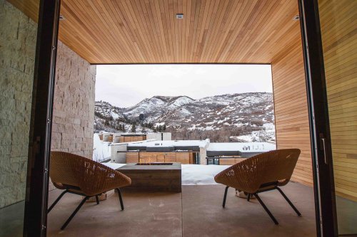 A modern patio with two chairs overlooking snowy mountains and a contemporary landscape.