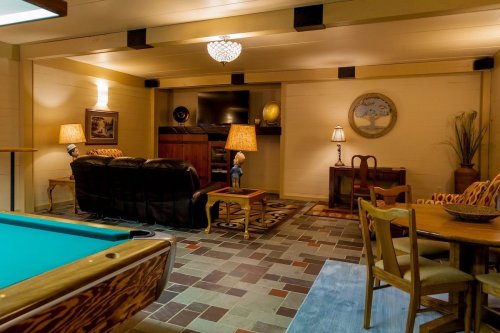Cozy interior with a pool table, seating area, lamps, and a TV, featuring warm lighting and a rustic design.