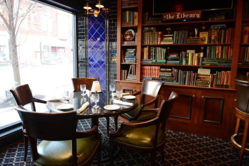 A cozy dining area with a round table set for four, surrounded by a bookshelf filled with books.
