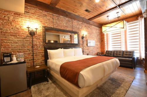 Cozy hotel room with a brick wall, a large bed, a sofa, and modern lighting.