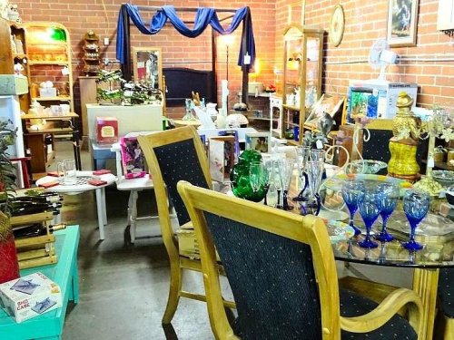 A cozy antique shop filled with various vintage items, furniture, and decorative glassware.