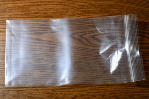 A clear, resealable plastic bag laid flat on a wooden surface.