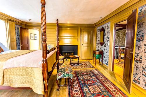Cozy bedroom with a four-poster bed, fireplace, patterned rugs, and vintage decor. Warm, inviting atmosphere.