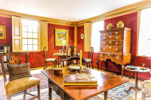 Cozy room with red wallpaper, wooden furniture, a dining table, and decorative items, illuminated by natural light.