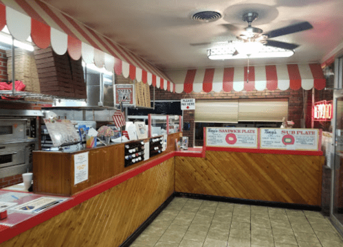 A cozy diner interior with a red and white striped awning, menu boards, and a counter displaying food items.