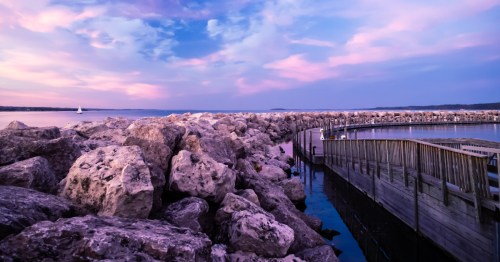 A scenic overlook of a covered pavilion pier jutting into the wavy turquoise water of Traverse City.