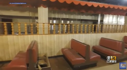 Interior of an empty diner featuring red booths and wooden railings, with a retro design and muted lighting.