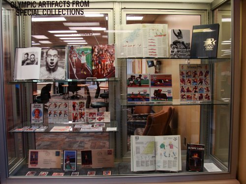 Display case featuring Olympic artifacts, including photos, posters, and memorabilia from various Olympic events.