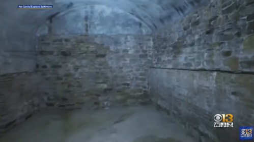 A dimly lit stone room with arched ceilings and rough, textured walls.
