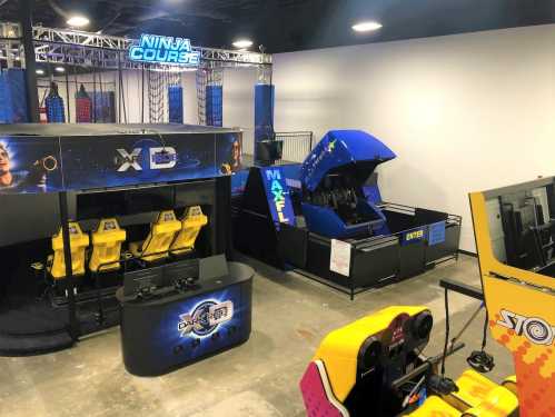 An arcade featuring a Ninja Course, a dark ride, and various gaming stations in a spacious entertainment area.