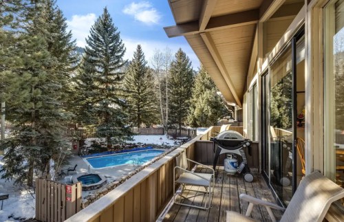 View from a balcony overlooking a snowy landscape with a pool and trees in a serene setting.