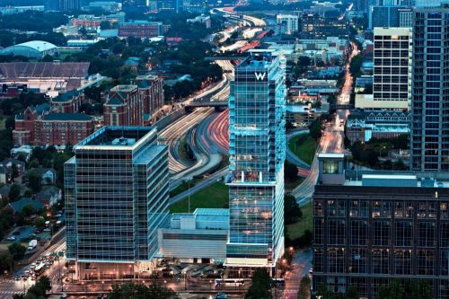 Aerial view of city skyline featuring modern glass buildings and busy highways at dusk.