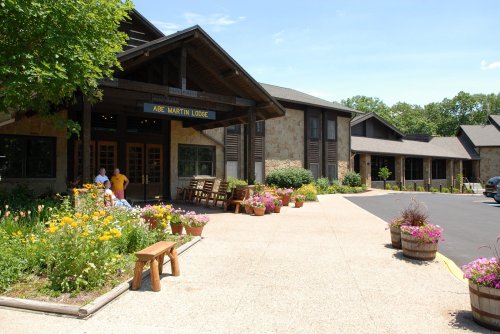 A scenic lodge entrance surrounded by colorful flowers and greenery on a sunny day.