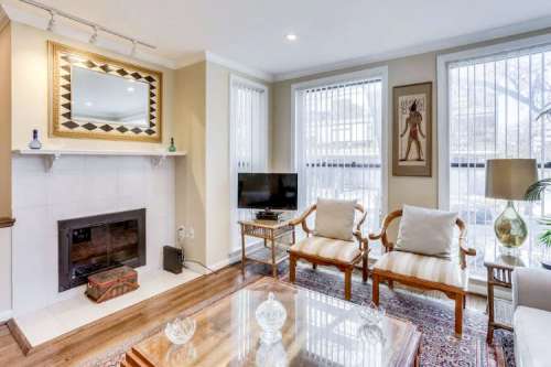 Cozy living room with a fireplace, two chairs, a coffee table, and large windows letting in natural light.