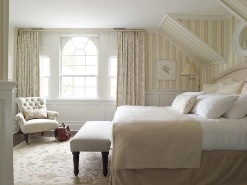 Bright, cozy bedroom with a large window, elegant curtains, a plush bed, and a comfortable armchair.