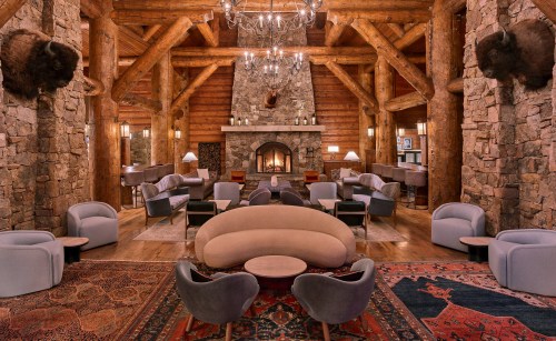 Cozy lodge interior with stone walls, wooden beams, a fireplace, and stylish seating arrangements. Warm, inviting atmosphere.