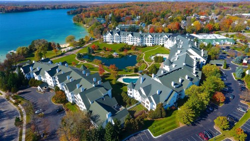 Aerial view of a resort complex surrounded by colorful autumn trees and a serene lake.