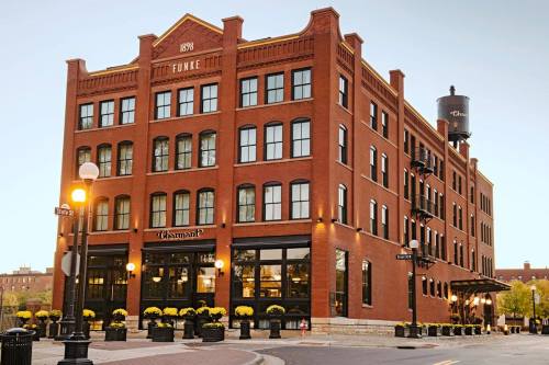 Historic red brick building with large windows, featuring a water tower and outdoor seating with yellow flowers.